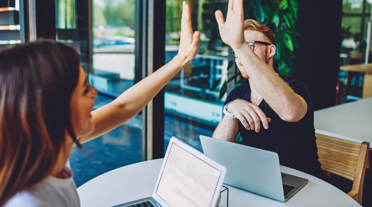 Two people sitting across a desk, high fiving